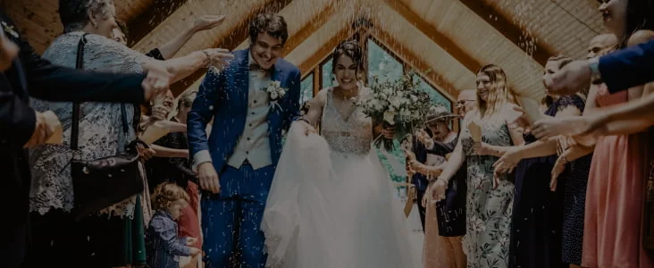 Un couple de mariés traverse une haie d’invités qui leur lancent des confettis.