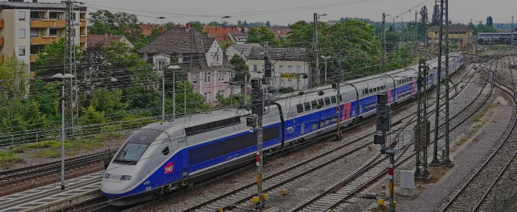 Un TGV bleu et gris circule sur des voies ferrées.